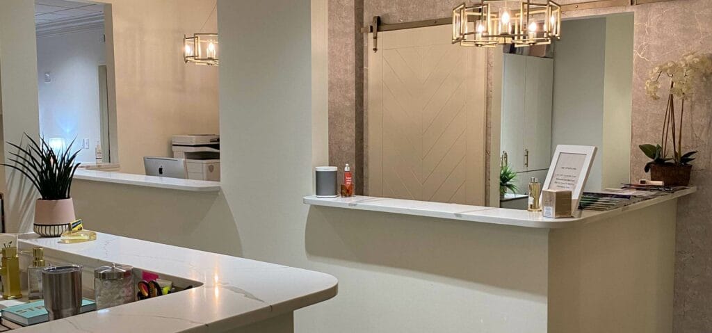 Modern, clean reception area featuring white counters, elegant lighting, and minimalist decor