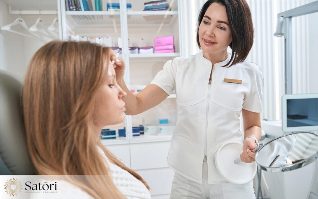 Female patient consulting with a dermatologist about acne treatment, with the doctor examining her skin closely.
