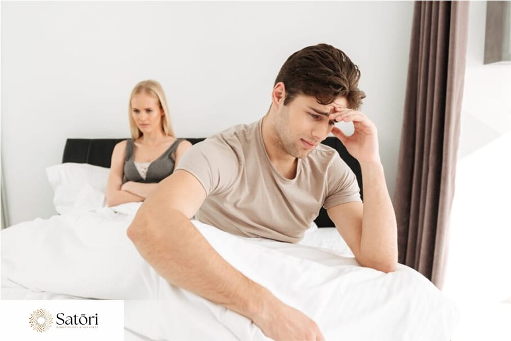 Disappointed couple sitting on bed facing sexual dysfunction and intimacy issues.
