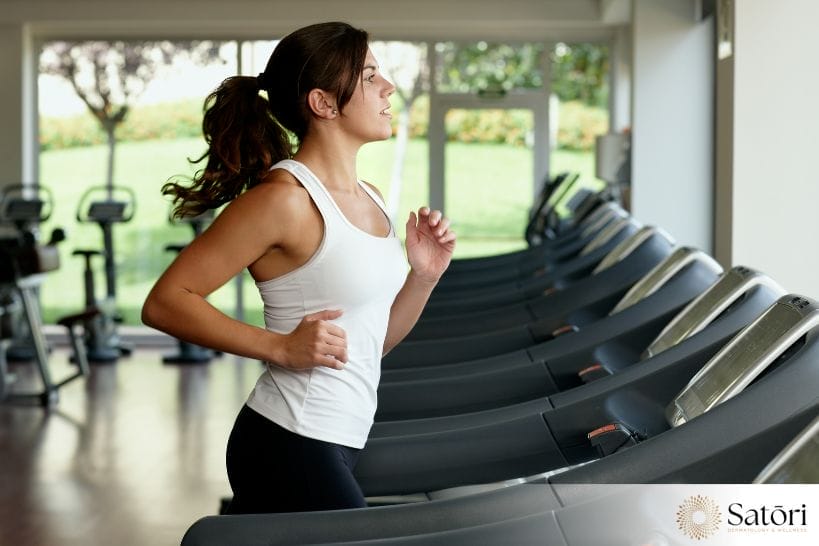 Woman running on a treadmill during a cardio workout to support fitness, circulation, and cellulite-focused wellness goals